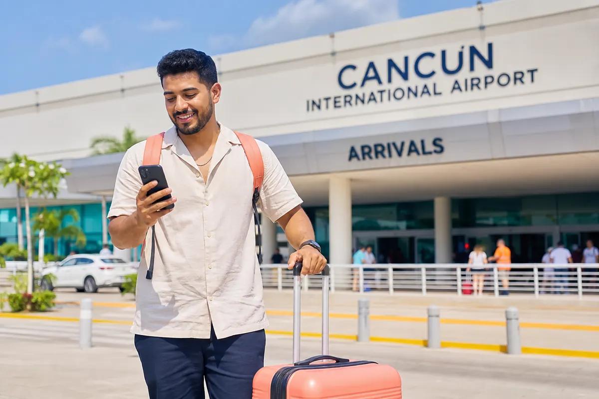 Smiling traveler looking at his phone outside the arrivals hall of an international airport