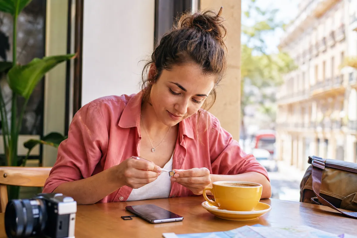 Voyageur nettoyant les contacts dorés d'une carte SIM avec un coton-tige.