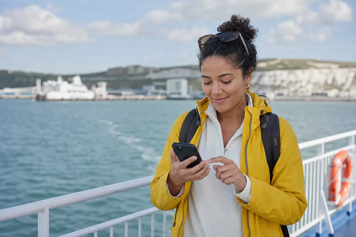 Traveler on a ferry activating their eSIM connection on a smartphone.